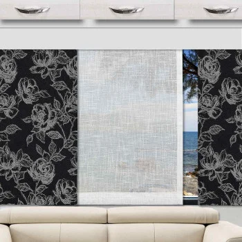 Ein Wohnwagenfenster ist mit dreiteiligen Jalousien ausgestattet, wobei die beiden äußeren Paneele in Schwarz mit weißen Blumenmustern verziert sind und sich in der Mitte ein durchsichtiges weißes Paneel befindet. Unter dem Fenster steht ein beiges Sofa. Draußen sind ein ruhiges Meer und Bäume zu sehen.