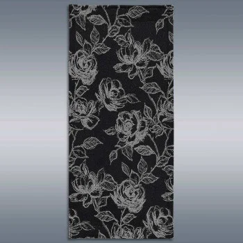 Ein rechteckiges Stück schwarzen Stoffes zeigt ein detailliertes Blumenmuster mit weißen Umrissen von Rosen und Blättern, die gleichmäßig über die Oberfläche verteilt sind. Der Hintergrund besteht aus einem subtilen grauen Farbverlauf, der das Muster akzentuiert.