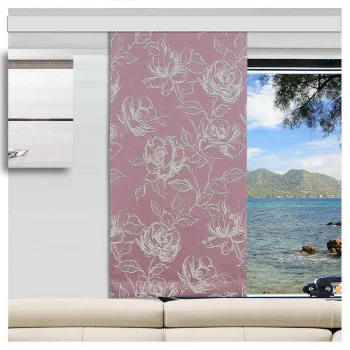 Ein Caravan mit einem hellbeigen Sofa vor einem Fenster. Das Fenster hat einen rosafarbenen, blumengemusterten Vorhang, der teilweise zur Seite gezogen ist und den Blick auf ein blaues Meer, eine felsige Küste, grüne Bäume und ferne Berge unter einem klaren Himmel freigibt.