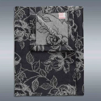 Eine gefaltete schwarze Tischdecke mit einem silbernen Blumenmuster ist vor einem glatten grauen Hintergrund mit Farbverlauf abgebildet. Eine Ecke der Tischdecke ist umgeschlagen, so dass die Rückseite des Stoffes sichtbar wird.