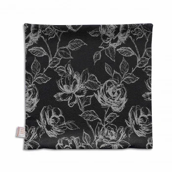 Eine quadratische schwarze Kissenhülle zeigt ein weißes Blumenmuster mit Rosen und Blättern. Das Muster besteht aus feinen Linien, die einen Kontrast zu dem dunklen Hintergrund bilden. An einem Rand ist ein kleines Stoffschildchen angebracht.
