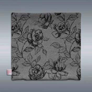 Ein quadratisches graues Kissen zeigt ein schwarzes florales Muster aus Rosen und Blättern. Der Hintergrund zeigt einen grauen Farbverlauf. Ein kleines genähtes Etikett befindet sich am unteren linken Rand des Kissens.