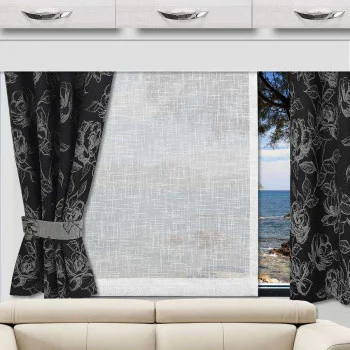 Ein Wohnwagenfenster mit durchsichtigen weißen Vorhängen in der Mitte und zurückgebundenen schwarzen Vorhängen mit Blumenmuster auf beiden Seiten. Die Außenansicht zeigt ein blaues Meer, eine felsige Küste und Baumzweige. Über dem Fenster befinden sich weiße Schränke mit silbernen Griffen.