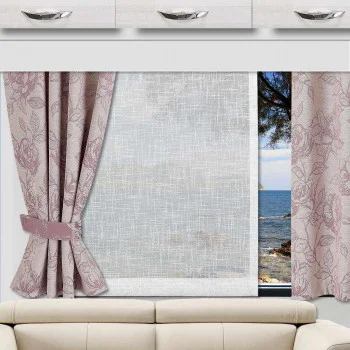 Ein Fenster über einem beigen Sofa wird von rosa geblümten Vorhängen gesäumt, von denen ein Teil zurückgebunden ist. Ein durchsichtiger weißer Vorhang bedeckt die Mitte des Fensters und verdeckt teilweise den Blick auf blaues Wasser, eine felsige Uferlinie und einen Baum. Über dem Fenster sind weiße Schränke angebracht