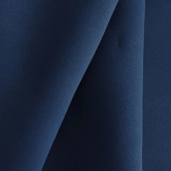 Nahaufnahme eines blauen Dekostoffs, der in weichen Falten drapiert ist und sanfte Schatten erzeugt.