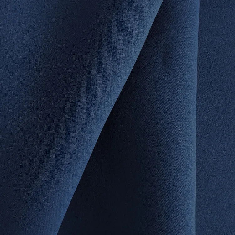 Nahaufnahme eines blauen Dekostoffs, der in weichen Falten drapiert ist und sanfte Schatten erzeugt.