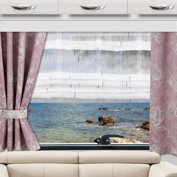 Unter einem Fenster mit rosa Vorhängen mit Blumenmuster steht ein beiges Sofa. Durch das Fenster sind eine felsige Küste und das Meer zu sehen. Ein Bild von Holzplanken versperrt den Blick teilweise, wodurch ein vielschichtiger visueller Effekt entsteht.