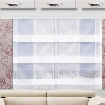 Ein Fenster ist mit einem weißen, durchsichtigen Vorhang mit horizontalen, blickdichten Streifen verhängt. An beiden Seiten des Fensters rahmen Vorhänge mit rosa Blumenmuster das Fenster ein. Darüber befinden sich drei weiße Schränke mit Metallgriffen, und unten ist teilweise ein beiges Sofa zu sehen.