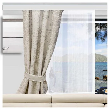Eine Nahaufnahme der SeGaTeX Caravan-Schiebegardine „Lykke“ hebt deren glänzende Effektstreifen hervor, wobei hinter einem beigen Sofa ein weißer, transparenter Vorhang und der Meerblick zu sehen sind.