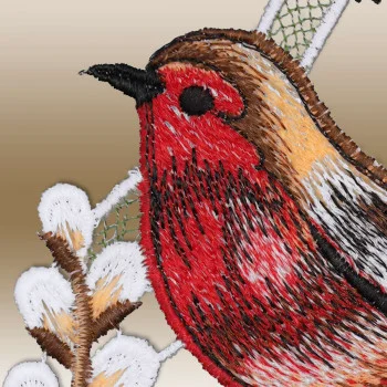 Detailansicht, die den gestickten Vogel in Rot, Braun und Gelb zeigt, der auf einem Zweig mit weißen Knospen vor einem zartbeigen Hintergrund sitzt.