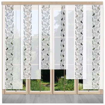 Weiße Flächenvorhänge mit blauem und grauem Blattmuster hängen vor großen Glastüren, die den Blick auf einen üppigen grünen Garten freigeben. Die Paneele bestehen abwechselnd aus gemustertem und einfarbigem, durchsichtigem Stoff.