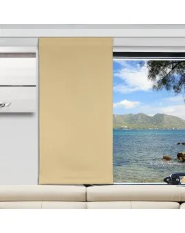 Ein beiger Vorhang verdeckt die Hälfte eines großen Fensters. Durch das Glas sind ein blaues Meer, eine felsige Küste, ferne grüne Berge und ein teilweise bewölkter Himmel zu sehen. Im Inneren des Raums steht ein weißes Sofa unterhalb des Fensters, und ein Teil eines weißen Wandregals ist zu sehen.