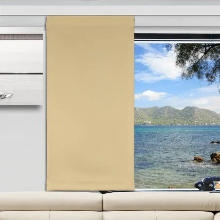 Ein beiger Vorhang verdeckt die Hälfte eines großen Fensters. Durch das Glas sind ein blaues Meer, eine felsige Küste, ferne grüne Berge und ein teilweise bewölkter Himmel zu sehen. Im Inneren des Raums steht ein weißes Sofa unterhalb des Fensters, und ein Teil eines weißen Wandregals ist zu sehen.