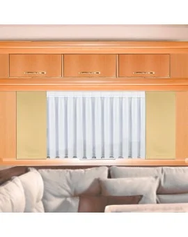 Innenansicht mit einem beigen Sofa mit Kissen im Vordergrund, hellen Holzschränken mit goldenen Griffen darüber und einem mittig angeordneten Fenster mit weißen Vorhängen, die von cremefarbenen Paneelen eingerahmt sind.