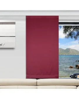 Ein modernes Wohnzimmer mit einem cremefarbenen Sofa, einem weinroter Vorhang, der ein großes Fenster teilweise verdeckt, und einem Blick nach draußen auf das Meer mit Bergen und Bäumen. An der linken Wand hängt ein weißes und graues abstraktes Kunstwerk.
