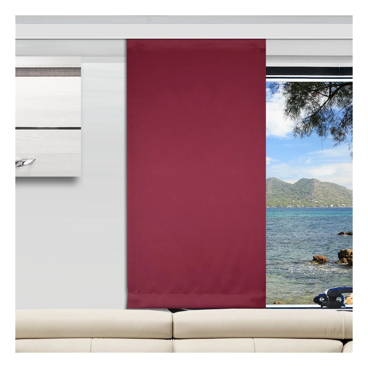 Ein modernes Wohnzimmer mit einem cremefarbenen Sofa, einem weinroter Vorhang, der ein großes Fenster teilweise verdeckt, und einem Blick nach draußen auf das Meer mit Bergen und Bäumen. An der linken Wand hängt ein weißes und graues abstraktes Kunstwerk.