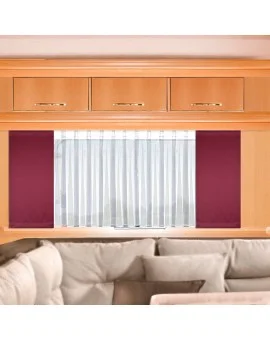 Ein heller Holzschrank mit drei Schubladen und goldenen Griffen ist über einem Fenster mit weißen Vorhängen und weinroten Seitenwänden angebracht. Unter dem Fenster ist teilweise ein beigefarbenes Sektionssofa mit Plüschkissen zu sehen.