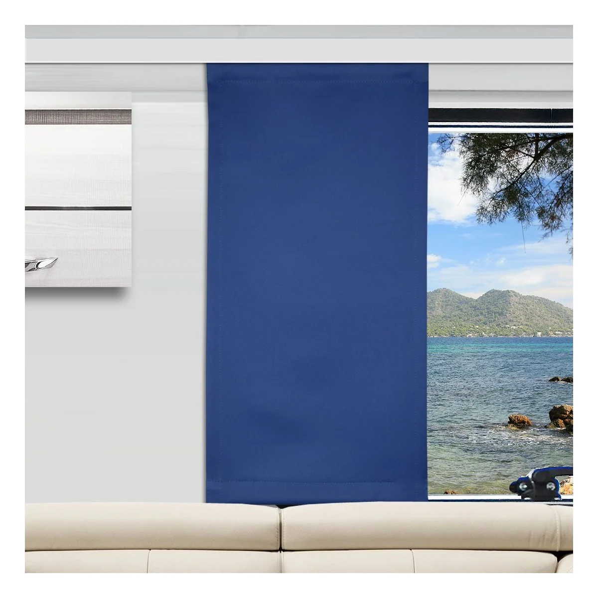 Ein modernes Wohnzimmer mit einem beigen Sofa und einem blauen Flächenvorhang, der ein Fenster teilweise verdeckt. Das Fenster bietet einen Blick auf ein ruhiges Meer, grüne Berge in der Ferne und einen klaren Himmel. Links neben dem Fenster befindet sich ein gerahmtes Wandkunstwerk.