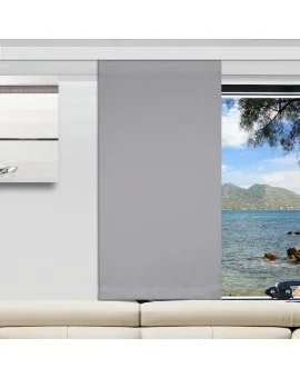 In einem modernen Wohnzimmer ist ein hellgrauer Flächenvorhang teilweise über ein großes Fenster gezogen. Der freigelegte Teil des Fensters zeigt blaues Wasser, eine felsige Küste, grüne Bäume und ferne Berge unter einem hellen Himmel. Davor steht ein beiges Sofa.