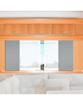 Ein heller Holzschrank mit vier Schubladen ist über einem Fenster angebracht. Das Fenster hat graue und weiße Seitenteile, durch den eine undeutliche Außenansicht zu sehen ist. Unter dem Fenster befindet sich ein weißes Sofa mit mehreren hellen Kissen.