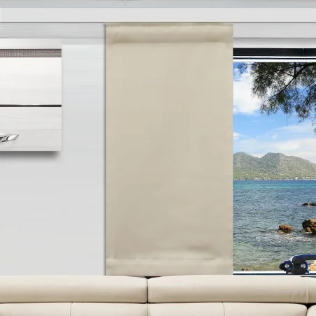 Ein beiger Flächenvorhang ist teilweise über ein Fenster hinter einem weißen Sofa gezogen und verdeckt die linke Seite. Die rechte Seite des Fensters zeigt blaues Wasser, eine felsige Küste, grüne Hügel und einen Baumzweig unter einem hellen Himmel. An der linken Wand befindet sich ein modernes Kunstwerk.