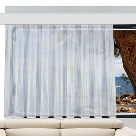 Der Store MAILIN bedeckt ein großes Fenster. Durch den Vorhang sind das Meer, eine felsige Küste und ein Baum zu sehen. Im Vordergrund erscheint der obere Teil eines cremefarbenen Sofas unterhalb des Fensters.