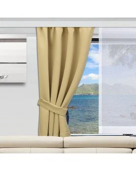 Ein beiger Vorhang ist an einer Seite zugezogen und gibt teilweise den Blick auf ein großes Fenster frei, durch das man das Meer, den blauen Himmel und die Berge in der Ferne sieht. Unter dem Fenster steht ein weißes Sofa, daneben ist ein weißer Schrank an der Wand montiert.