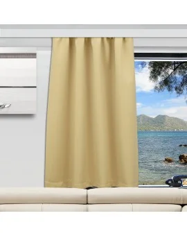 Ein beiger Vorhang ist teilweise über ein großes Fenster in einem modernen Wohnzimmer mit einem weißen Sofa gezogen. Durch das Fenster blickt man auf das Meer, die Berge und die Äste der Bäume unter einem blauen Himmel mit vereinzelten Wolken.