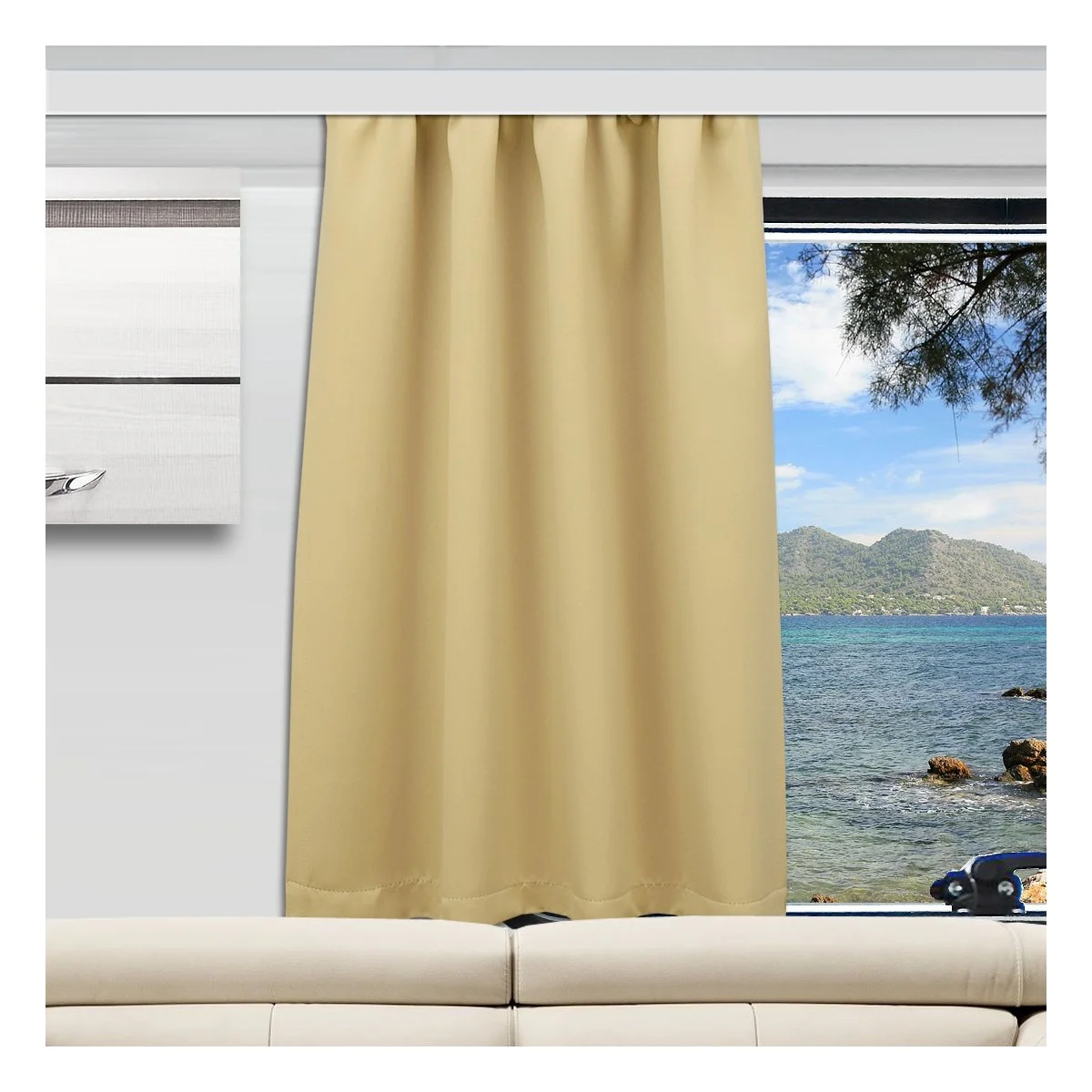 Ein beiger Vorhang ist teilweise über ein großes Fenster in einem modernen Wohnzimmer mit einem weißen Sofa gezogen. Durch das Fenster blickt man auf das Meer, die Berge und die Äste der Bäume unter einem blauen Himmel mit vereinzelten Wolken.