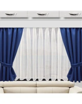 In der Mitte befindet sich ein Fenster mit weißen Vorhängen, die zu beiden Seiten dunkelblaue Verdunkelungsvorhänge haben, die mit passenden blauen Bändern gesichert sind. Über dem Fenster sind drei weiße Schubladen mit silbernen Griffen angebracht, und darunter steht ein beiges Sofa.