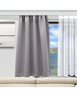 Ein grauer Vorhang bedeckt die Hälfte eines modernen Fensters und versperrt teilweise den Blick auf blaues Wasser und grüne Hügel. Auf der rechten Seite verdeckt ein durchsichtiger weißer Vorhang die andere Hälfte des Fensters. Am unteren Rand des Bildes steht ein beiges Sofa.