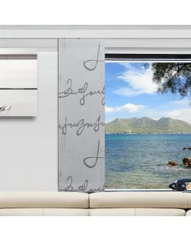 In einem Wohnzimmer stehen eine weiße Couch und ein grau gemusterter Vorhang, der ein großes Fenster teilweise verdeckt. Draußen sieht man das blaue Wasser des Ozeans, die felsige Küste, ferne Berge und einen teilweise bewölkten Himmel, an dem rechts oben Äste zu sehen sind.