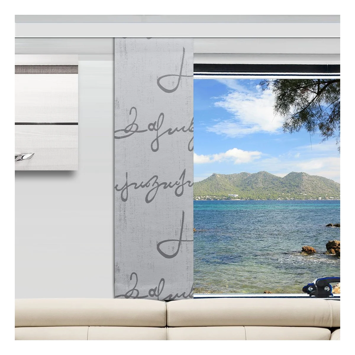 In einem Wohnzimmer stehen eine weiße Couch und ein grau gemusterter Vorhang, der ein großes Fenster teilweise verdeckt. Draußen sieht man das blaue Wasser des Ozeans, die felsige Küste, ferne Berge und einen teilweise bewölkten Himmel, an dem rechts oben Äste zu sehen sind.