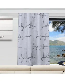 In einem modernen Wohnzimmer steht ein weißes Sofa vor einem Fenster. Ein Vorhangpaneel zeigt ein weißes und graues Holzmaserungsmuster mit schwarzem kursivem Text. Der Blick nach draußen umfasst das Meer, Berge, Bäume und einen Himmel mit vereinzelten Wolken.