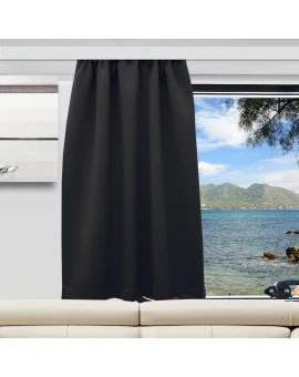 Ein schwarzer Vorhang verdeckt die obere Hälfte eines Fensters, das sich über einem hellbeigen Sofa befindet. Der unbedeckte untere Teil zeigt ein blaues Meer, eine felsige Küste, ferne grüne Berge und einen teilweise bewölkten Himmel.
