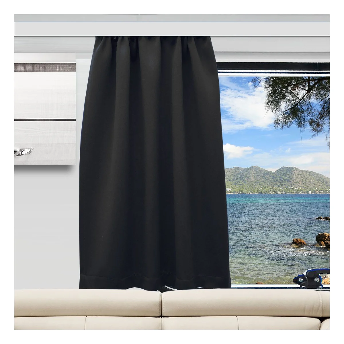 Ein schwarzer Vorhang verdeckt die obere Hälfte eines Fensters, das sich über einem hellbeigen Sofa befindet. Der unbedeckte untere Teil zeigt ein blaues Meer, eine felsige Küste, ferne grüne Berge und einen teilweise bewölkten Himmel.