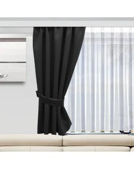 Ein Wohnzimmerfenster ist mit durchsichtigen weißen Vorhängen und einem einzelnen dicken schwarzen Vorhang, der mit einem Raffhalter zur Seite gezogen wird, verhüllt. Ein Teil eines weißen Sofas und ein an der Wand befestigtes modernes Kunstwerk sind unterhalb und links des Fensters zu sehen.