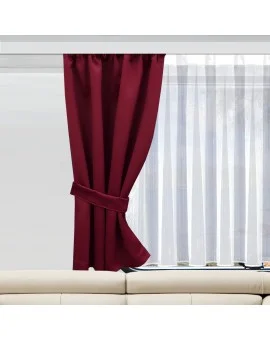 Ein weinroter Vorhang, der an einer Seite mit einem passenden Raffhalter befestigt ist, verdeckt teilweise ein Fenster, das mit durchsichtigen weißen Vorhängen versehen ist. Unter dem Fenster befindet sich ein beiges Sofa. Der Raum wird durch natürliches Licht erhellt.