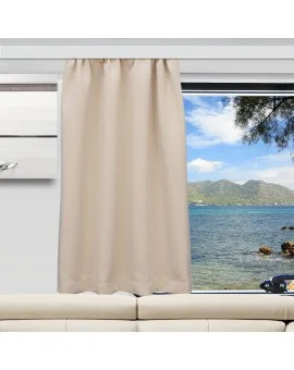 Ein beiger Vorhang verdeckt einen Teil eines großen Fensters. Durch das Fenster sind ein blaues Meer, eine felsige Küste, grüne Hügel und ein teilweise bewölkter Himmel zu sehen. Im Inneren des Raums steht ein weißes Sofa unter dem Fenster, und ein Teil einer an der Wand montierten Klimaanlage ist zu sehen.