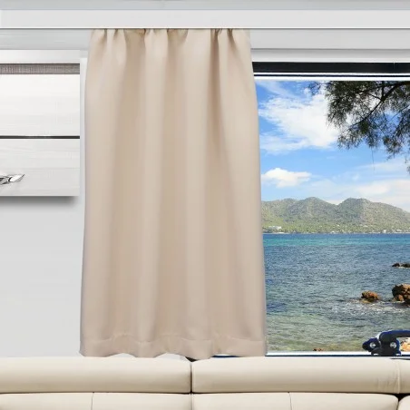 Ein beiger Vorhang verdeckt einen Teil eines großen Fensters. Durch das Fenster sind ein blaues Meer, eine felsige Küste, grüne Hügel und ein teilweise bewölkter Himmel zu sehen. Im Inneren des Raums steht ein weißes Sofa unter dem Fenster, und ein Teil einer an der Wand montierten Klimaanlage ist zu sehen.