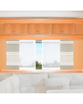 Helle Holzschränke mit silbernen Griffen sind über einem Fenster angebracht, das mit weißen und gestreiften Jalousien versehen ist. Außerhalb des Fensters sind grüne Bäume zu sehen. Im Vordergrund ist ein Teil einer weißen Couch mit hellen Polstern zu sehen.