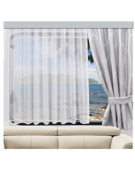 Ein weißer durchsichtiger Vorhang bedeckt ein Fenster und lässt Licht herein. Ein grauer Vorhang ist an einer Seite zurückgebunden. Durch das Fenster sind ein ruhiges Meer, ferne Hügel und Bäume zu sehen. Das Fenster befindet sich über einer beigen Couch. Der Raum scheint gut beleuchtet zu sein.