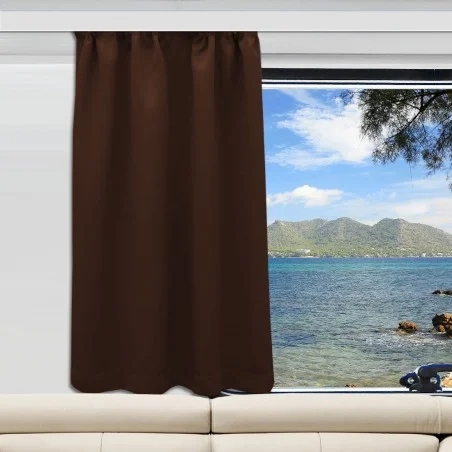 Ein brauner Vorhang ist an einem Fenster, das sich über einem beigen Sofa befindet, teilweise geöffnet. Das Fenster gibt den Blick auf ein blaues Meer, eine felsige Küste, grüne Berge in der Ferne und einen teilweise bewölkten Himmel frei. Von der rechten Seite ragt ein Baumast in die Szene hinein.